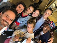 a group of people standing next to each other holding guitars and smiling at the camera