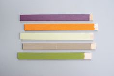 four different colors of wood are arranged on a white surface, one is purple, the other is green