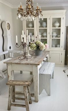 a dining room table with two stools and a chandelier hanging from the ceiling