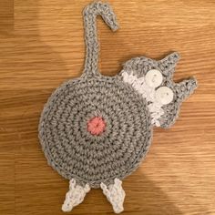 a crocheted bird with two buttons on it's back sitting on a wooden surface