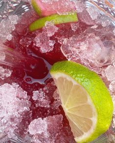 two limes are on top of ice and one is cut in half with a lemon wedge