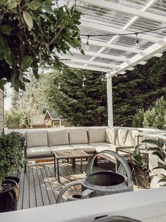 an outdoor living area with couches, tables and potted plants on the deck