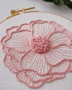 a close up of a pink flower on a white hoop with flowers in the background