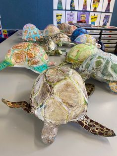 several turtles made out of plastic bags sitting on a table in front of children's books