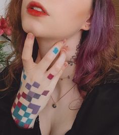 a woman with purple hair and tattoos on her arm, holding her hand up to her face