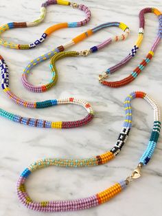 the multicolored beaded necklaces are laid out on a marble countertop