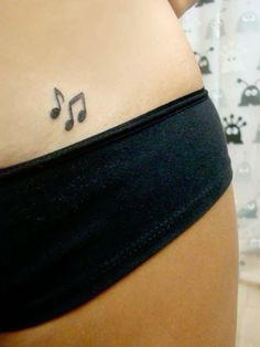 a woman's stomach with musical notes tattoo on the side of her lower back