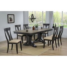 a dining room table with six chairs and a rug on the floor in front of it