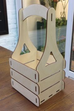 a wooden toy carrier sitting on top of a wooden table next to a glass door