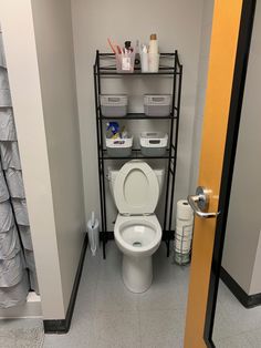 a white toilet sitting in a bathroom next to a metal rack filled with containers and bottles