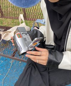 a person sitting on a bench with a camera in their hand and some other items