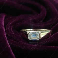 an engagement ring sitting on top of a purple velvet cloth with a diamond in the center