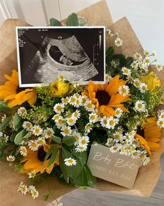 a bouquet of sunflowers and daisies in front of a birth announcement card