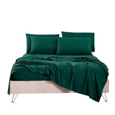 a bed with green sheets and pillows on it