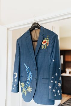 a blue blazer with embroidered stars and moon on it hanging in front of a kitchen