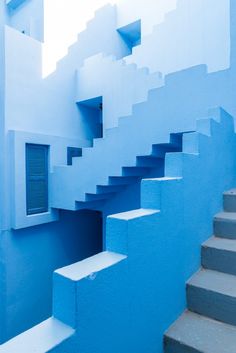 stairs leading up to a window in a blue building with white walls and concrete steps