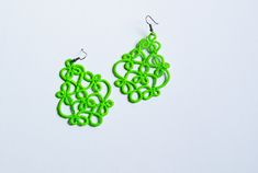 a pair of green earrings sitting on top of a white surface