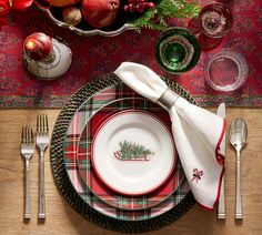 a place setting with plaid napkins, silverware and christmas decorations on the table