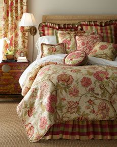 a bedroom with a bed, dresser and window covered in floral print fabric on the walls