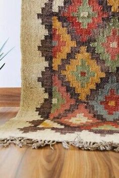 an old rug is sitting on the floor next to a potted plant in a vase