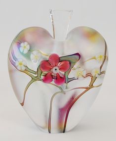 a heart shaped vase with flowers painted on the outside and inside, sitting against a white background