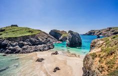 the beach is surrounded by rocks and blue water