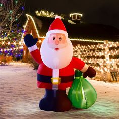 a large inflatable santa clause standing on top of snow covered ground next to christmas lights