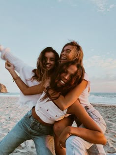 two young women are hugging on the beach