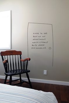 a black rocking chair sitting in front of a white wall with writing on the walls