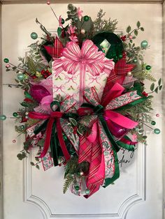 a christmas wreath on the front door decorated with pink, green and red ribbon bows