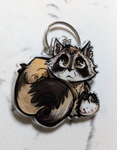 a keychain with a drawing of a raccoon on it's back