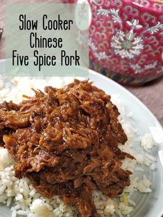 slow cooker chinese five spice pork with rice on a white plate next to a red and pink vase