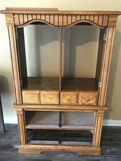 an old wooden china cabinet with glass doors and drawers on the bottom shelf, in front of a wall