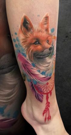 a woman's leg with a fox and dream catcher tattoo on it