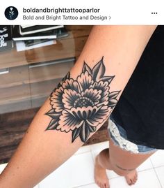 a woman's leg with a flower tattoo on her left arm and the words bold bright tattoo parlor below it