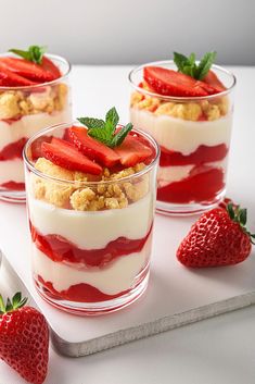 three desserts with strawberries and cream on a tray