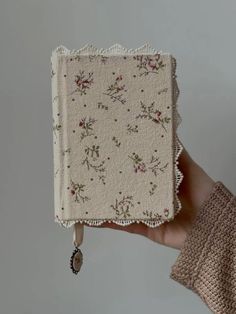 a person holding up a small book with flowers on it's front and sides