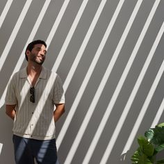 a man standing in front of a wall with his hands on his hips and looking to the side