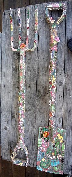 there is a pair of garden tools hanging on the side of a wooden fence with flowers all over it