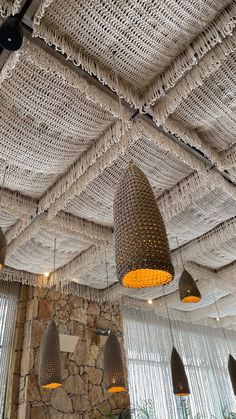 several lamps hanging from the ceiling in a restaurant with stone walls and windows behind them