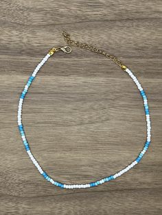 a blue and white beaded bracelet on a wooden surface with a gold plated clasp