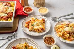 three white plates with lasagna casserole and other dishes on the table