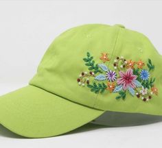 a green hat with embroidered flowers on it