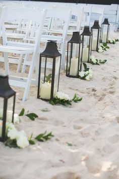 a row of white chairs sitting next to each other on top of a sandy beach