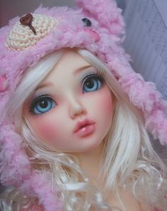 a close up of a doll wearing a pink hat