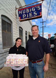 a man and woman standing in front of a building with bags of rice on the street