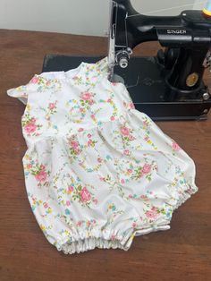 Darling  Bubble Romper made from a vintage sheet.  50/50 Cotton/Poly blend comes out of the drier looking like this!  This romper is so precious I'm tempted to keep it for a future grandchild. Delicate rose pattern on white, snaps at the back and at the crotch. Fully lined bodice, elasticized leg openings.  Shoulder to crotch: 16.5 inches Bodice width: 9.5 inches Leg opening (without stretching) 9.5 inches All vintage and repurposed  materials are thoroughly cleaned and inspected. You made notice taylor markings on the clothing made during construction.  These are water soluble and will wash out easily. Fitted Cotton Bloomers With Ruffles, Sleeveless Fitted Bubble Romper With Floral Print, Fitted Cotton Bubble Romper With Ruffles, Fitted Bubble Romper With Ruffles And Short Sleeves, Fitted Short Sleeve Bubble Romper With Ruffles, Floral Print Fitted Cotton Bubble Romper, White Bubble Romper With Ruffles And Short Sleeves, Bodice Pattern, Capped Sleeves