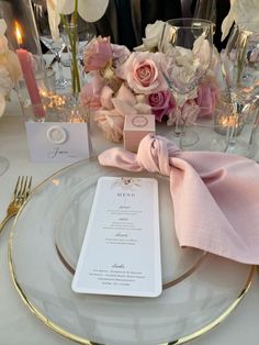 the table is set with pink and white flowers, silverware, and napkins