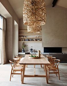 a dining room table with chairs and a wooden light fixture hanging from it's ceiling