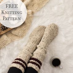 a pair of knitted socks sitting on top of a white rug next to a cup of coffee